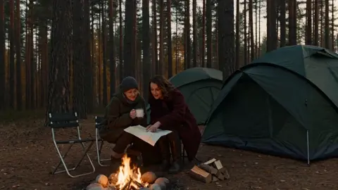 *Две женщины 40–45 лет, подруги, сидят у костра возле двух…